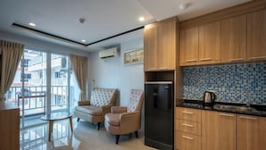 A modern kitchen with wooden cabinets, a black refrigerator, and a tiled backsplash. - New Nordic Trend 4 by Apartwell (Pattaya)
