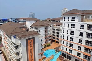 A multi-story hotel with balconies, a swimming pool, and a clear sky. - New Nordic Trend 4 by Apartwell (Pattaya)