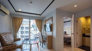 A modern hotel room with a sofa, a TV, a dining table, and a view of the city. - New Nordic Trend 4 by Apartwell (Pattaya)