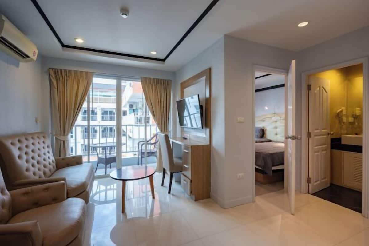 Una habitación de hotel moderna con sofá, televisión, mesa de comedor y vistas a la ciudad.