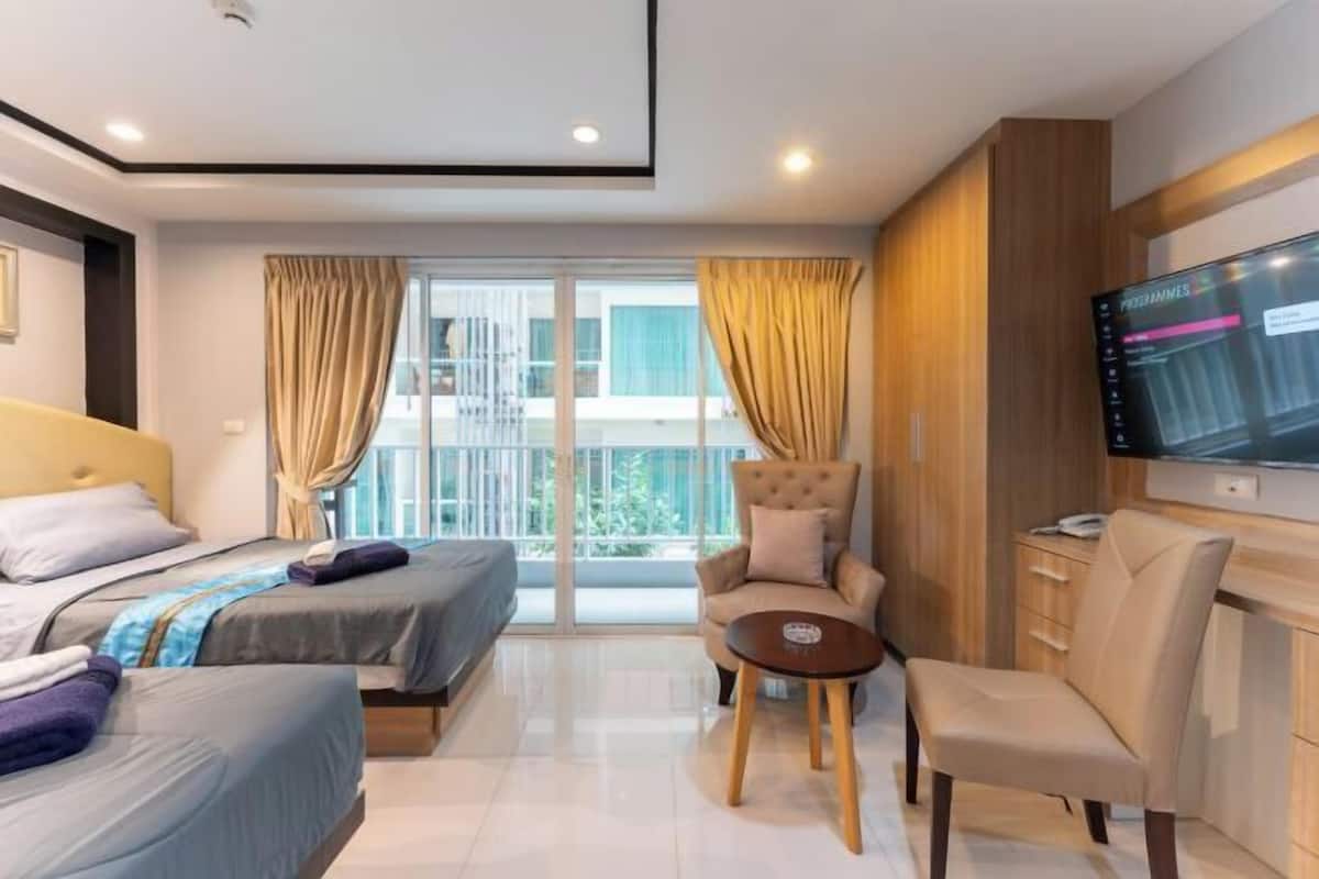 Una habitación de hotel moderna con dos camas, un sofá, un televisor y un balcón con cortinas.