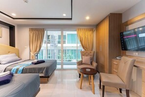 Una habitación de hotel moderna con dos camas, un sofá, un televisor y un balcón con cortinas.