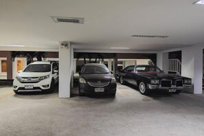 A parking garage with three cars parked under a white ceiling with ventilation grilles. - New Nordic Trend 4 by Apartwell (Pattaya)