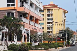 A multi-story hotel with balconies, a red roof, and a well-maintained garden area. - New Nordic Trend 4 by Apartwell (Pattaya)