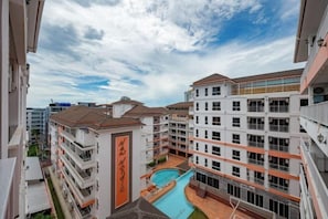 Un edificio de varios pisos con piscina, balcones y cielo despejado.
