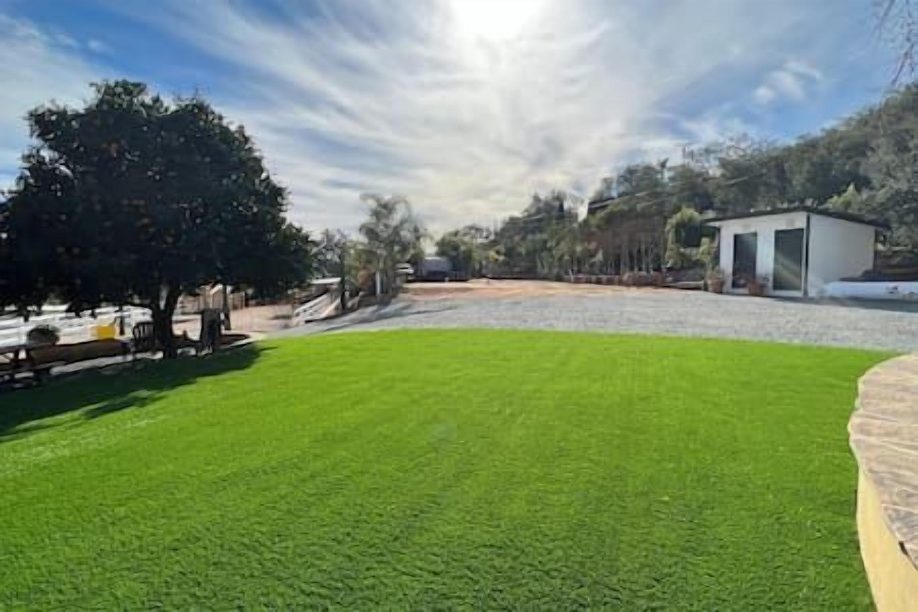 A well-maintained lawn with a small building in the background.