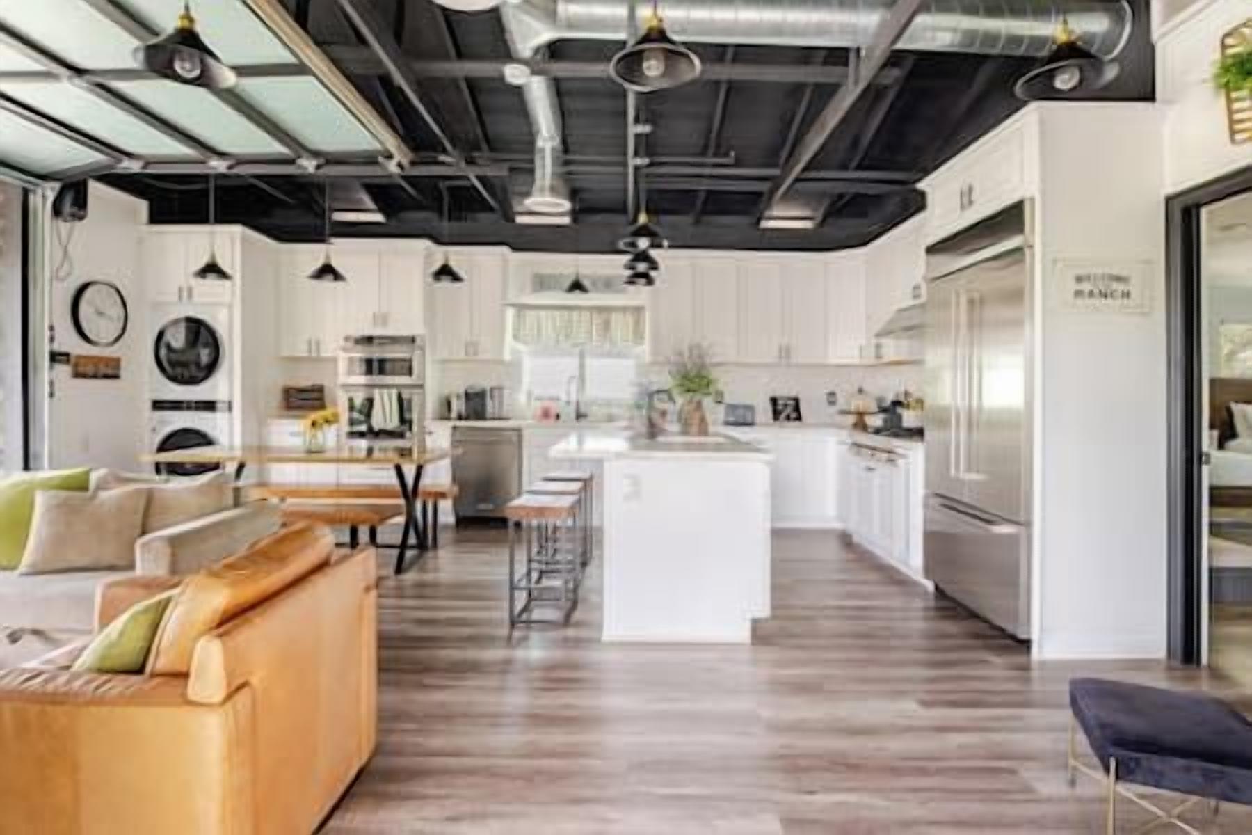 A modern kitchen with white cabinets, a central island, and stainless steel appliances.