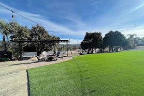A well-maintained lawn, a covered patio area, and a clear blue sky.