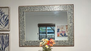 A dining table with two chairs, a vase with flowers, and a mirror with a decorative frame. - City Unit 4 Walk to Esplanade (Cairns North)