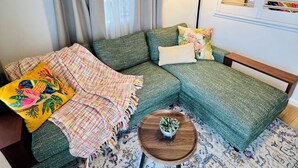 A cozy living room with a sectional sofa, a patterned rug, and a small wooden coffee table. - City Unit 4 Walk to Esplanade (Cairns North)