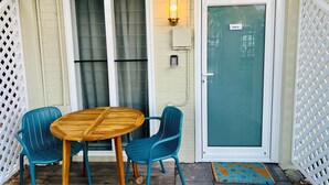 A small patio with a wooden table and two chairs, a sliding glass door, and a white fence. - City Unit 4 Walk to Esplanade (Cairns North)
