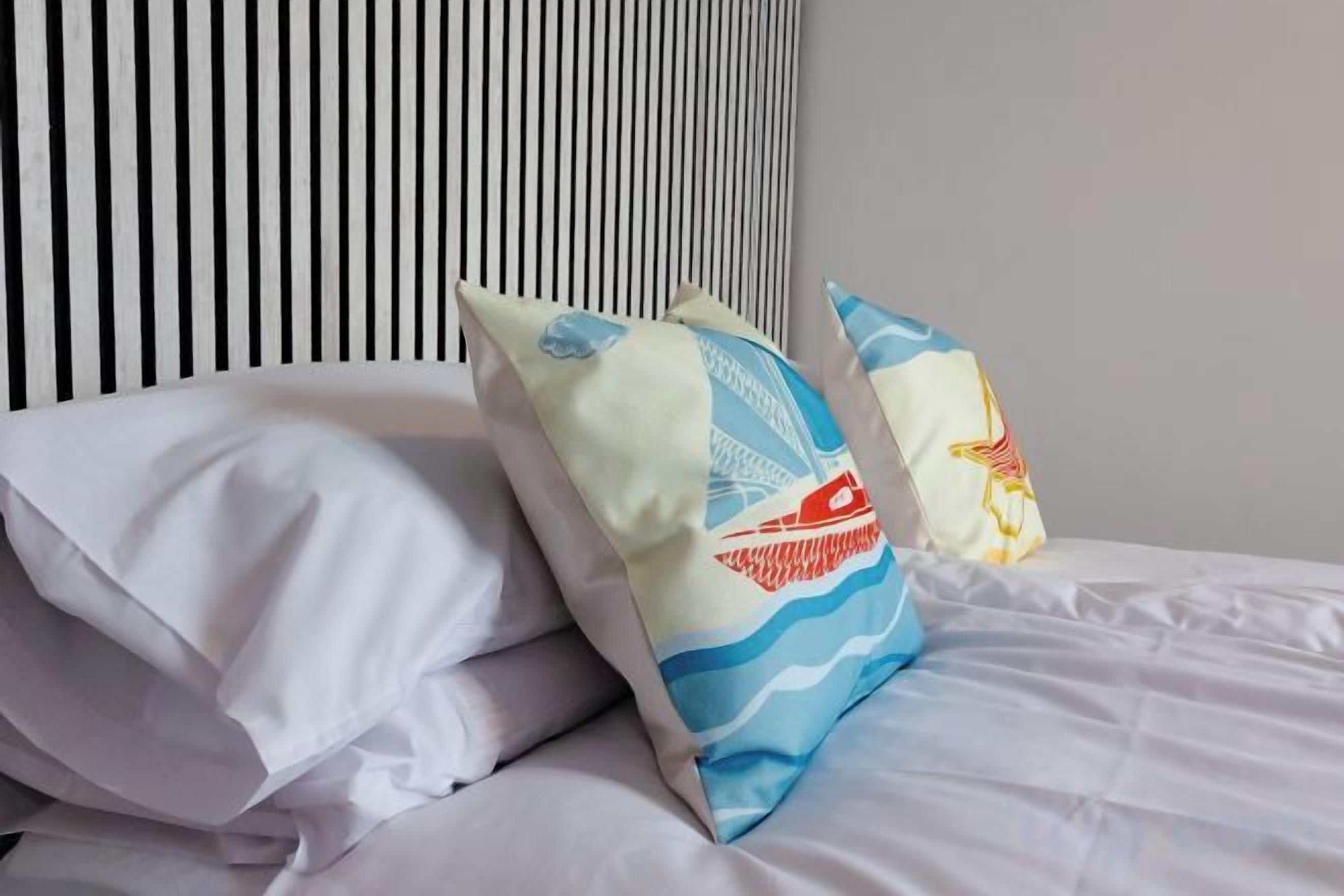 A bed with white bedding and decorative pillows.