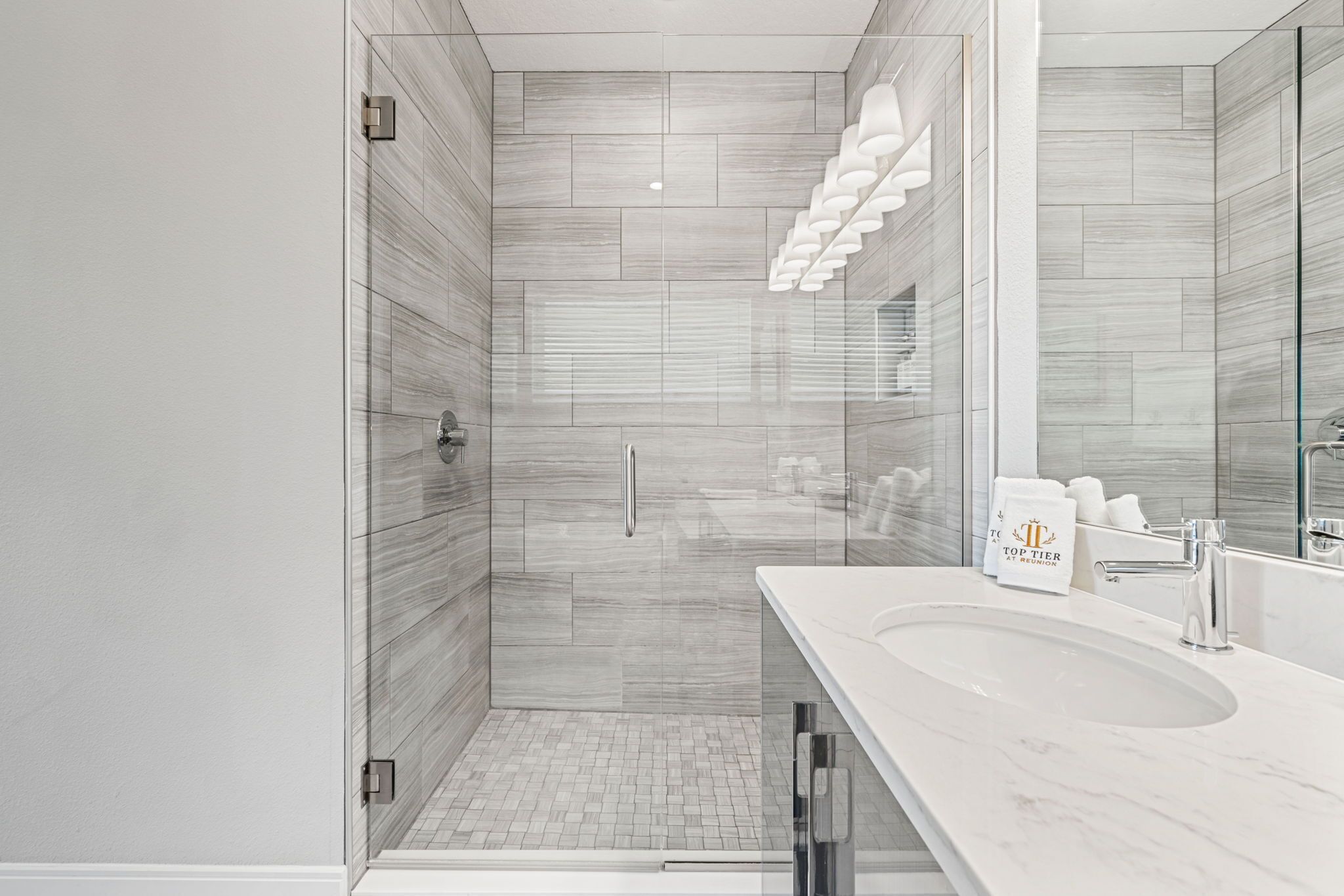 A modern bathroom with a glass shower enclosure, a large sink, and a mirror.