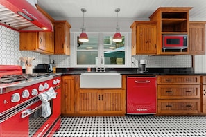 A kitchen with wooden cabinets, a red stove, a red refrigerator, and a black and white tiled floor. - Dahlia House: 3 BDRM home in Highlands, NC, just a short walk to town. (Highlands)