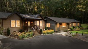 A row of wooden cabins with a covered porch and a stone pathway leading to the entrance.
