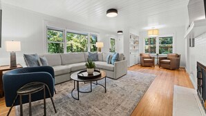 A spacious living room with a large sofa, a coffee table, and a fireplace. - Dahlia House: 3 BDRM home in Highlands, NC, just a short walk to town. (Highlands)