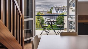 Une chambre moderne avec un balcon, une table à manger et deux chaises.
