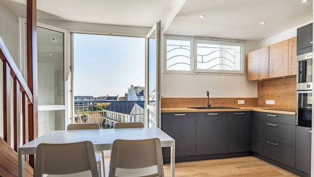 Une cuisine moderne avec un coin repas, de grandes fenêtres et une vue sur la ville.
