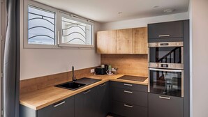 Une cuisine moderne avec des meubles de couleur sombre, un plan de travail en bois, un évier noir et des appareils électroménagers en acier inoxydable.