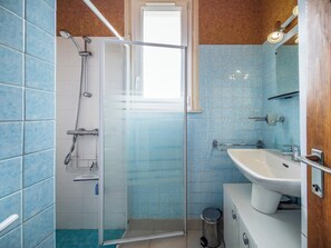 Une salle de bain avec une douche à parois de verre, un lavabo et un miroir.
