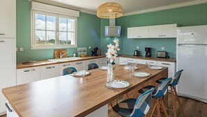 Een moderne keuken met een houten kookeiland, witte kasten en een groot raam.