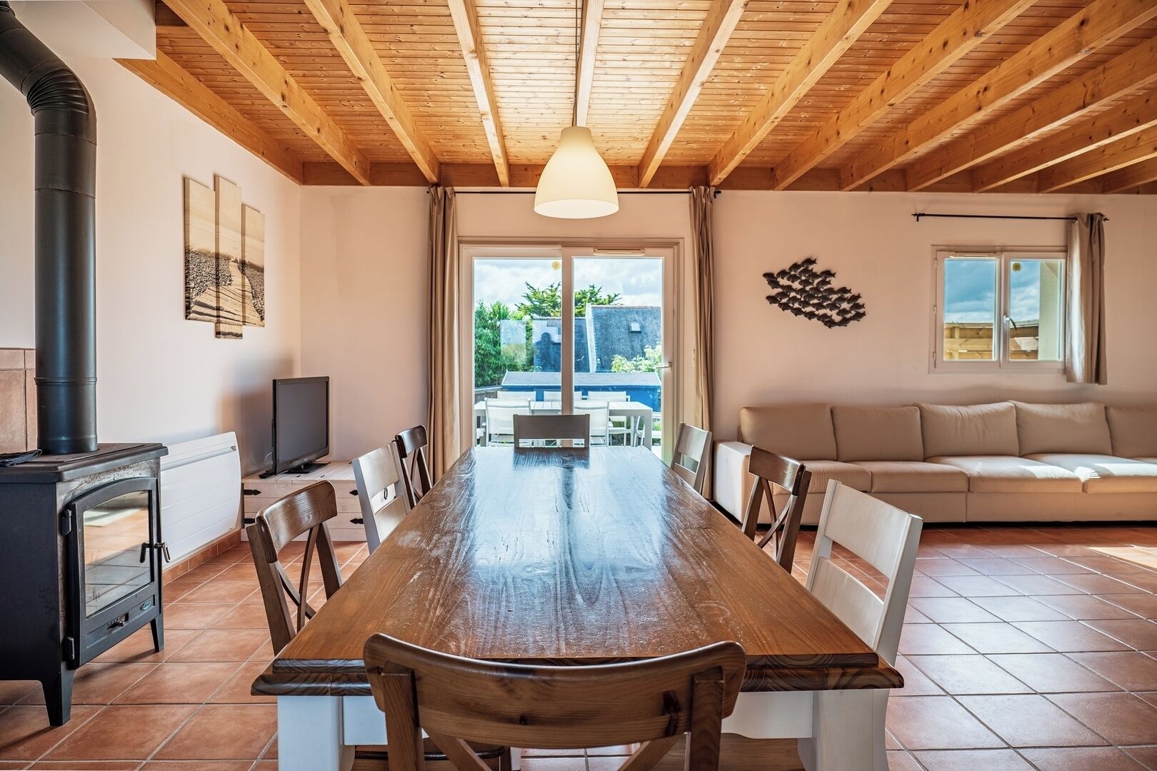 A spacious dining area with a long wooden table, chairs, a TV, and a fireplace.