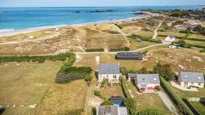 Vista aerea di una zona residenziale costiera con case, una spiaggia e camper parcheggiati lungo la riva.
