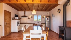 Una cucina con un tavolo di legno, sedie, un fornello e una finestra con vista.