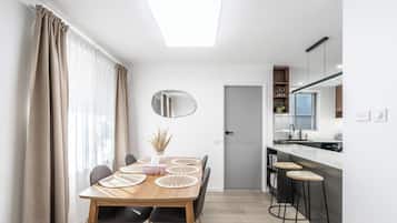 Une cuisine moderne dotée d’un îlot central intégré, d’un coin repas avec une table et des chaises en bois, et d’un grand miroir au mur.