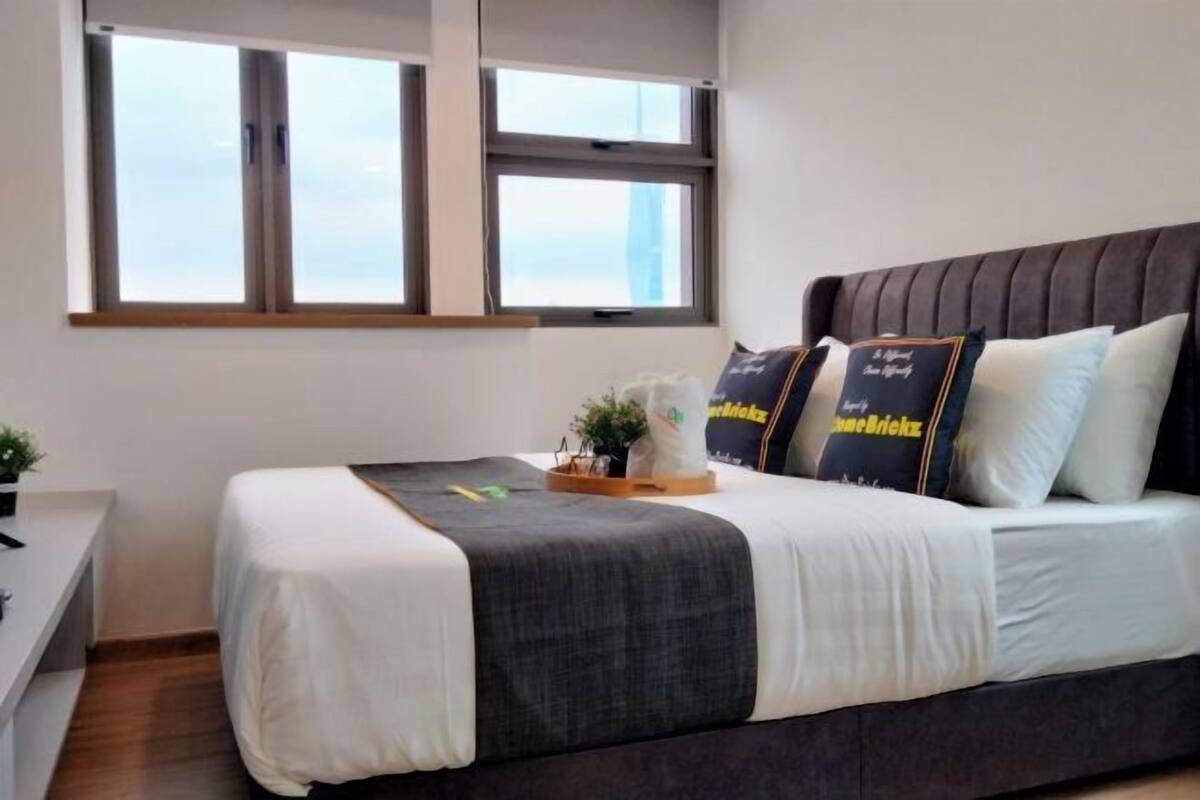 A modern hotel room with a large bed, a small desk, and a window with a city view.