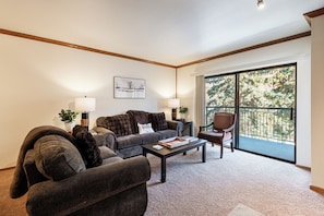 A living room with a sofa, armchair, coffee table, and a chair. There is a large window with a view of trees. - Park City Park Station 2B/2B Main Street / Community Hot Tub, Sauna, Pool! Skiing & Main Street (Park City)