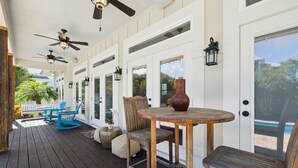 Eine überdachte Veranda mit Holzboden, Deckenventilatoren und Sitzgelegenheiten.