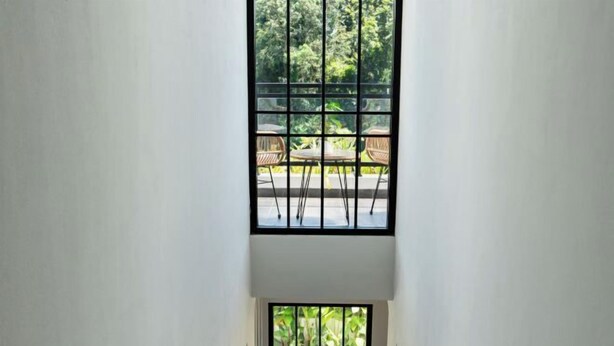 A high ceiling with a large window overlooking a pool and outdoor seating area. - Inori Villas (Bali)