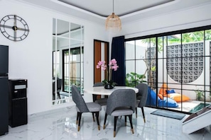 Un espace repas moderne avec une table ronde, des chaises et une vue dégagée grâce à de grandes fenêtres.