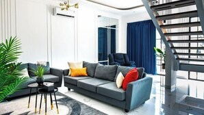 A modern living room with a sofa, a coffee table, and a staircase. - Inori Villas (Bali)