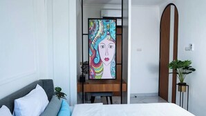 A modern bedroom with a bed, a desk, and a large abstract painting. - Inori Villas (Bali)