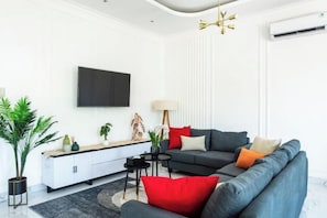 Un salon moderne comprenant un canapé, une table basse, un téléviseur et un buffet.