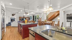 A spacious kitchen with a central island, wooden flooring, and a staircase leading to a loft area.