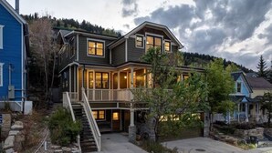 A two-story house with a front porch, a staircase, and a stone wall.