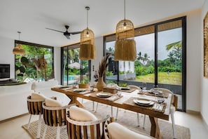 Un espace repas comprenant une grande table, des chaises et des luminaires suspendus.
