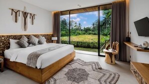 Un dormitorio con una cama grande, televisión y vistas a un jardín exuberante.
