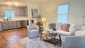 Ein modernes Wohnzimmer mit einem grauen Sofa, einem Couchtisch und einem gemusterten Teppich.