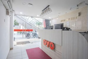 A reception area with a reception desk, a red mat, and a staircase leading to an outdoor area.