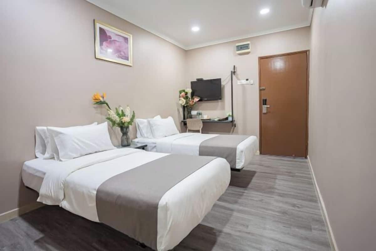 A hotel room with two beds, a flat-screen TV, a desk, and a door.
