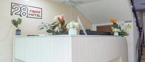 En moderne receptionsdisk med skærm og skilt med hotellets navn.