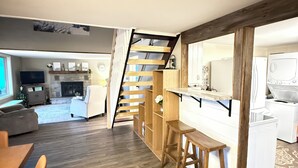 Ein modernes Interieur mit einer Holztreppe, einem Essbereich und einer Küche mit weißen Geräten.