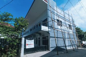 A building under construction with scaffolding, a RedDoorz sign, and a clear sky. - RedDoorz @ Aurea Apartelle (Iloilo City)