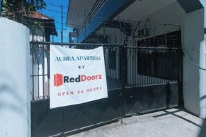 A gated entrance with a banner advertising a property for sale by RedDoorz, open 24 hours. - RedDoorz @ Aurea Apartelle (Iloilo City)