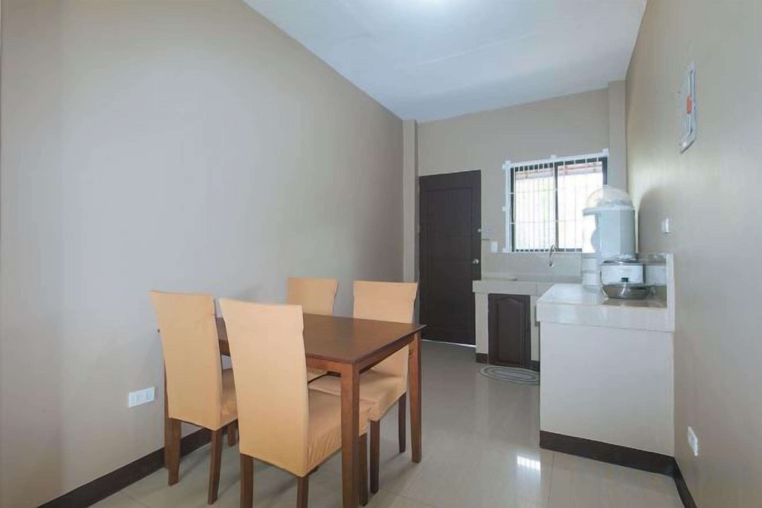 A dining area with a table and chairs, a kitchenette, and a door leading to another room.