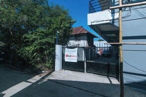 A gated area with a Red Doors sign, a metal fence, and a building with a red roof. - RedDoorz @ Aurea Apartelle (Iloilo City)